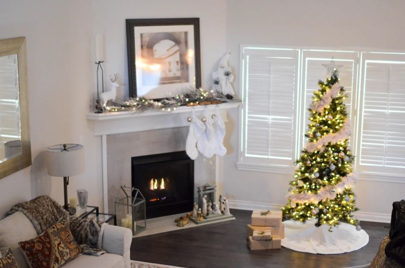 tree with garland near fireplace in white room